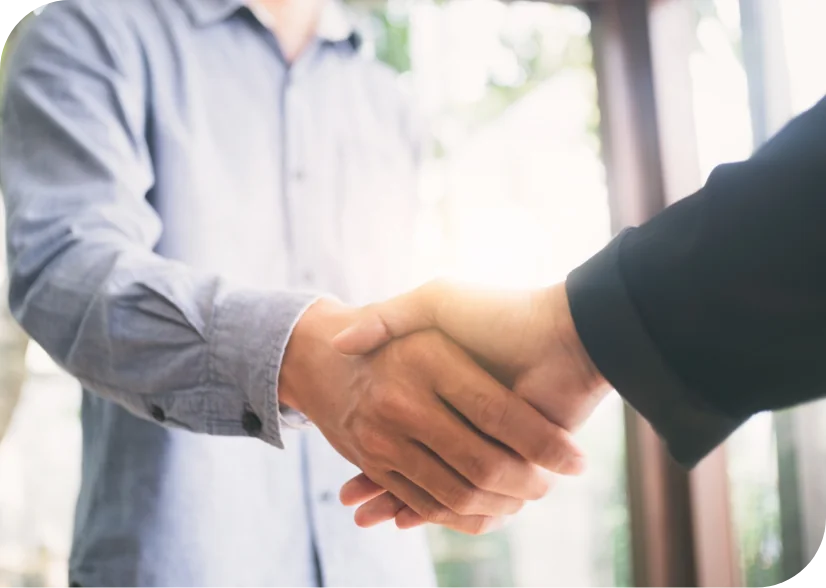 Two people shaking hands in a business setting, symbolizing a realtor partnership for termite inspections